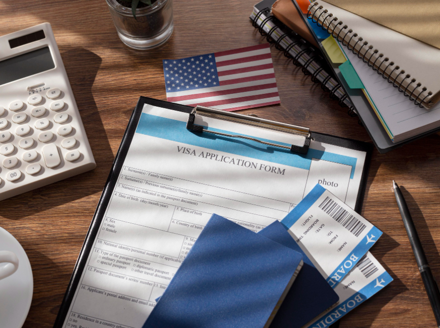 E-2 visa application documents with passport, boarding passes, U.S. flag, and visa application form on a desk.